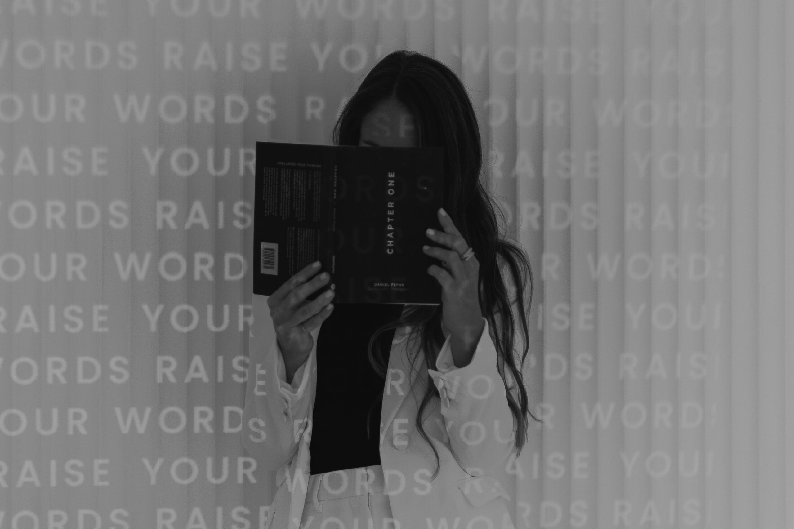 Woman reading a book against a background that says raise your words
